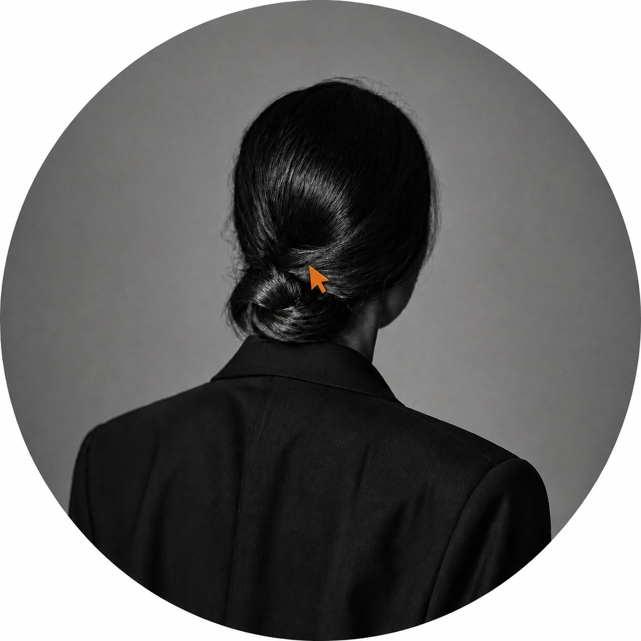 Black-and-white editorial portrait with an orange cursor-shaped hair clip